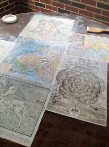 Gluing down the maps with Mod Podge.